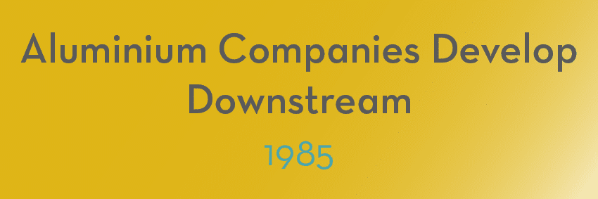A gradient background shifting from yellow to gold with bold gray text saying, "Aluminium Companies Develop Downstream" and a smaller turquoise text below saying, "1985 - Moments in Aluminium.